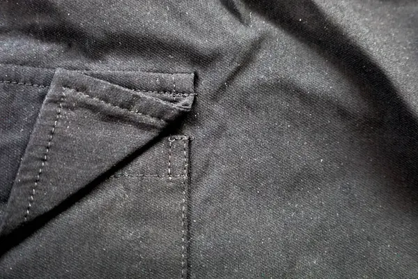 Siyah giysi elementinin detaylı bir yakın çekimi, kumaş katları ve dikişler sergileniyor. Görüntü, terzi kalitesini, malzeme dokusunu ve donanım detaylarını göstermek için idealdir.