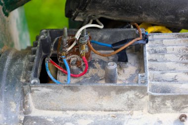 Yakın çekim karmaşık elektrik bağlantılarını gösteriyor: tozlu bir mekanizma üzerindeki paslı metal terminallere bağlı çok renkli kablolar. Bu, teknik yönünü ve eski ekipmanların bakım ve onarım ihtiyacını gösterir.