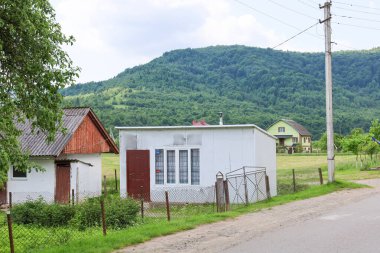 Skhidnitsa, Ukrayna, - 08 Haziran 2024: Yeşil tepeler ve ormanlar zeminine yayılmış çok sayıda evi olan bir kırsal alan.