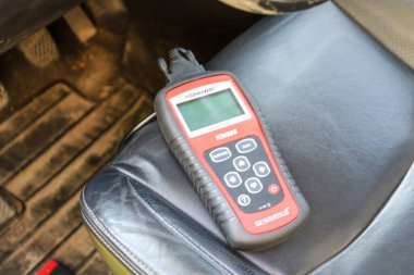 Urich, Ukrayna, - 08 Haziran 2024: Teşhis cihazı siyah deri bir araba koltuğunda, ekranı yukarı bakan.