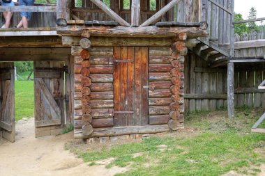 Antik ahşap yapılar, çoğaltıcı yapılar, güçlü ve otantik görünürler, solda açık bir geçit ve merkezde kapalı bir kapı vardır..