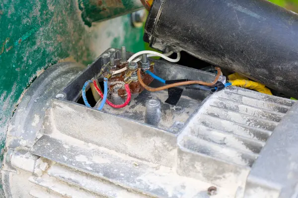 Renkli kablolar ve terminallerle bağlı açık bir elektrikli motor kutusu. Onarım ya da teftiş sürecini gösteriyor. Yüzeydeki toz ve aşınma izleri ekipmanların çalışma doğasını vurgular..