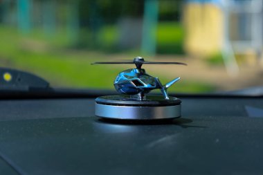 Oda spreyi görevi gören küçük metal bir helikopter modeli arabanın gösterge panelinde duruyor. Zarif tasarımı ve parlak yüzeyi iç kısma modern bir dokunuş katıyor.
