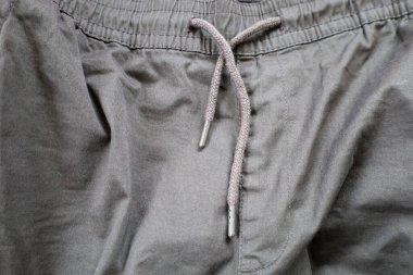 Siyah spor pantolonları, elastik bir kemer ve bağlamak için askılı bir ip. Kumaş dokusu ve bağlama ayrıntıları çok yönlü bir arkaplan oluşturur, spor kıyafetleri veya gündelik stil için uygundur.