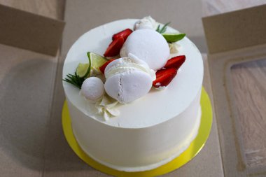 Zarif bir beyaz pasta taze çilekler, limon dilimleri, kremalar ve karton bir kutuya yerleştirilmiş biberiye filizleriyle süslenir. Bu tatlı bir kutlama ya da hediye için mükemmel..