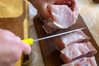 Eller tahtanın üzerinde taze et dilimliyor, daha fazla işlem için hazırlıyorlar. Bu resim gıda hazırlama sürecini veya mutfak bloglarını göstermek için uygundur, tazeliği ve elle çalışmayı vurgular.