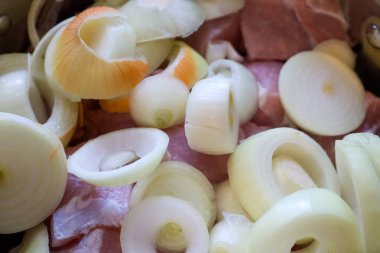 Yakın planda et parçaları ve marine edilmeye hazır büyük miktarda dilimlenmiş soğan görülüyor. Bu resim yemek blogları veya tarifler için idealdir, malzemelerin tazeliğini vurgulamak için..