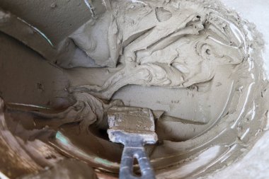 Ready-made building mortar and a master tool in a bucket. Cement mortar and trowel for construction work. A thick mixture used for laying tiles or leveling surfaces.