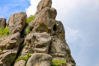 Bu çekim, farklı dokular ve gölgelerle gökyüzüne doğru yükselen devasa kayaları içerir. Yeşil bitki örtüsü ara sıra kayaları delip geçerek doğal dinamizmi ekliyor ve manzaradaki ihtişamlarını vurguluyor..