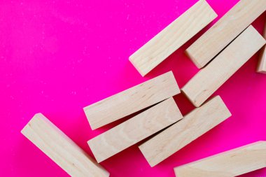 Doymuş bir fuşya arka planına rastgele dağılmış parlak ahşap bloklar çekici ve dinamik bir kompozisyon oluşturur..