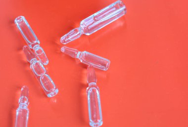 İçi sıvı dolu saydam cam ampuller parlak kırmızı bir zemine saçılmıştır. Camdan yansıyan ışık, parlak gölgeler yaratır..