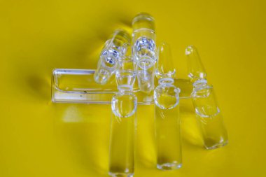 Tıptaki tıbbi hazırlıkları ve yenilikleri sembolize eden, canlı sarı bir zemin üzerinde açık tıbbi ampuller kümesi..