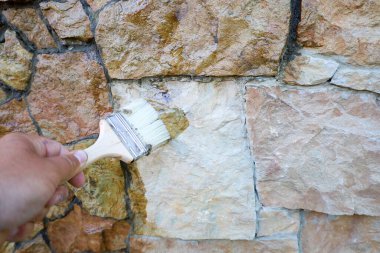 Temiz bir sıvı, doğal bir taş duvara fırçayla uygulanır, ıslak bir görünüm verir ve doğal rengini güçlendirir.. 