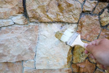 Bir fırça dış doğal taş duvar için temiz bir kaplama uygular. Düzensiz şekilli bloklardan oluşan duvar, yüzeyin dokusunu ve rengini yükselterek derin bir ıslak parıltı kazanır..