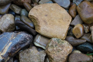Çeşitli şekillerde, boyutlarda ve renklerde taş ve çakıl taşlarının yakın çekimi. Doğal doku ve çeşitlilik arkaplan olarak kullanılabilecek ilginç bir zemin oluşturur..