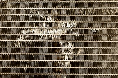 Bir araba radyatörünün yakın çekim dokusu. Metal yüzeyin birçok paralel plakası ve bazı hasarları vardır..