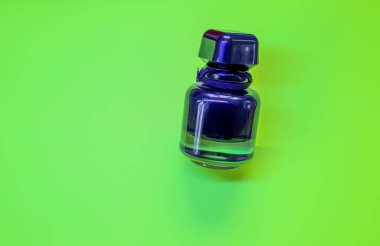 Siyah vücutlu ve mor şapkalı zarif bir parfüm şişesi. Bu kozmetik ürün yeşil zıt bir zemine yerleştirilmiştir..