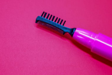 Sağlam bir arka planda parlak pembe kaş fırçası, canlı bir renk kombinasyonu yaratır. Bu kozmetik aksesuar kaş ve kirpik bakımı için mükemmel..