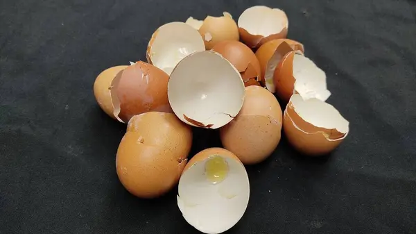 broken white chicken eggs on a black background