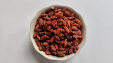 Beyaz arka planda izole edilmiş kasedeki kuru kırmızı üzümler..