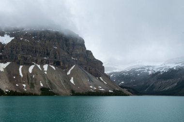 Kanada Banff Ulusal Parkı 'nda tepeleri karla kaplı güzel bir turkuaz göl.