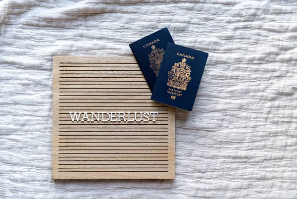 Üzerinde Kanada pasaportu olan beyaz harflerle bej renkli tahta bir tahtanın üzerinde gezinme tutkusu kelimesi.