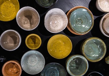 Üst görünüm, farklı renkler, şekiller ve boyutlarda el yapımı çanak çömlek kapları içeren masa eflatunu kompozisyonu.