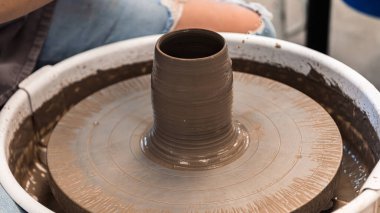 Çömlekçi çarkındaki el yapımı seramik kavanoz sürahisi çömlek atölyesinde kahverengi kil ile yapılır.