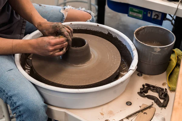 stock image Woman working on a pottery wheel shaping the brown clay with her hands