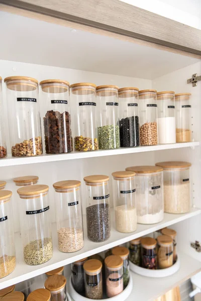 Neatly organized labeled food pantry in a home kitchen with spices grains flour rice sugar nuts