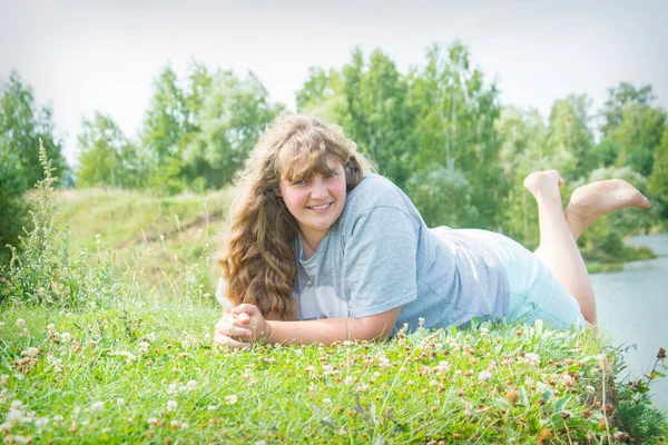 stock image In summer, a large, fat, overweight woman lies near the river.