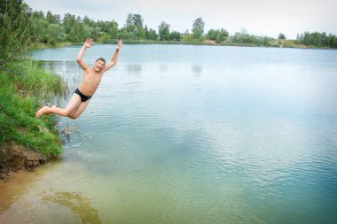 Yazın sahilde, mutlu bir çocuk nehre atlar..