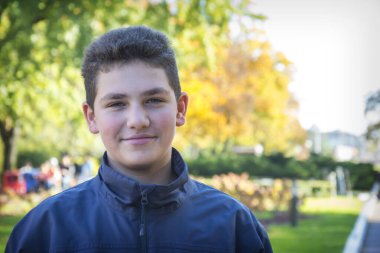 Sonbahar parkında mutlu bir çocuk duruyor.