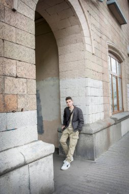 Baharda, yakışıklı, ciddi bir genç çocuk sokakta dikiliyor..