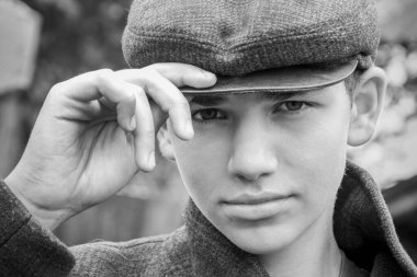 Yağmurlu bir günde köyde, şapkalı ve ceketli küstah görünüşlü yakışıklı bir adam. Siyah beyaz fotoğraf.