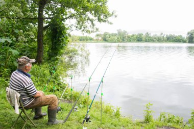 Yazın, yetişkin bir adam nehir kenarında oturur ve balık yakalar..