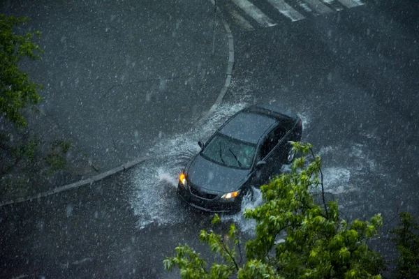 In summer, in rainy weather, the car drives in the rain. View from above.