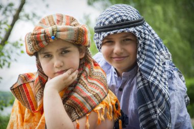 Erkek ve kız kardeş yazın Hindu ve Arap kostümü giyer. Şapkalı bir kız ve Arafatlı bir oğlan..