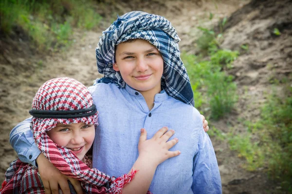 stock image Brother and sister in Hindu and Arabic costume in nature in summer. A girl in a hat and a boy in an Arafat.