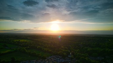 Yeşil tarlalar ve bulutlarla kırsal şehir üzerinde günbatımının havadan görünüşü.