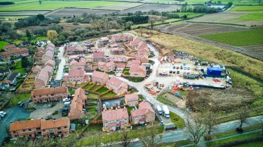 Etrafı tarlalarla çevrili evleri ve yolları olan bir banliyö manzarası..