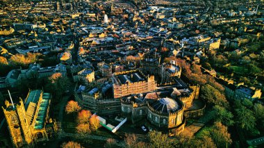 Altın saat boyunca genişleyen şehir manzarasının ortasında, mimari güzellik ve kentsel yoğunluğu gözler önüne seren tarihi Lancaster şatosunun havadan görünüşü..