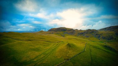 Güneşin bulutları delip geçtiği çarpıcı bir gökyüzü altında yemyeşil tarlaları olan manzaralı bir yer..