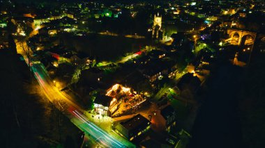 Knaresborough, Kuzey Yorkshire 'da hareket halindeki araçların ve aydınlatılmış binaların ışık yolları olan bir şehir kavşağının hava gece görüşü