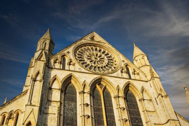 York, İngiltere 'de mavi gökyüzünün altında gül pencereli Gotik katedral cephesi.