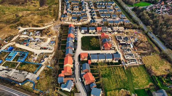 Aerial view of a suburban development with rows of houses, showing construction areas and completed homes with red roofs in Harrogate, North Yorkshire.