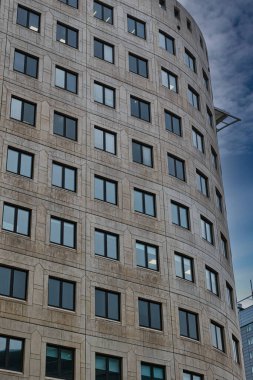 Leeds, İngiltere 'de açık mavi gökyüzüne karşı modern eğimli ofis binası cephesi.