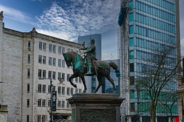 Modern binalar ve arka planında bulutlu gökyüzü olan Leeds, İngiltere 'de şehir merkezindeki binici heykeli.