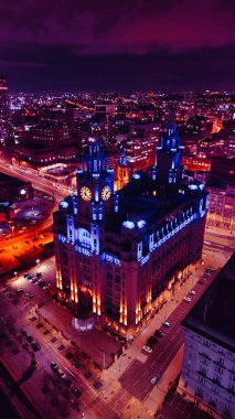 İngiltere, Liverpool 'da mor bir gökyüzüne karşı gece vakti aydınlık tarihi binayla dikey şehir manzarası.