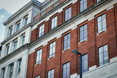 Büyük pencereleri ve dekoratif kornişleri olan klasik tuğla bina cephesi Leeds, İngiltere 'de açık bir gökyüzünün altında..